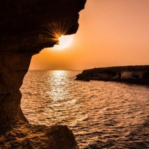 Breathtaking sunset over the ocean viewed from a Cyprus sea cave, creating a serene seascape.