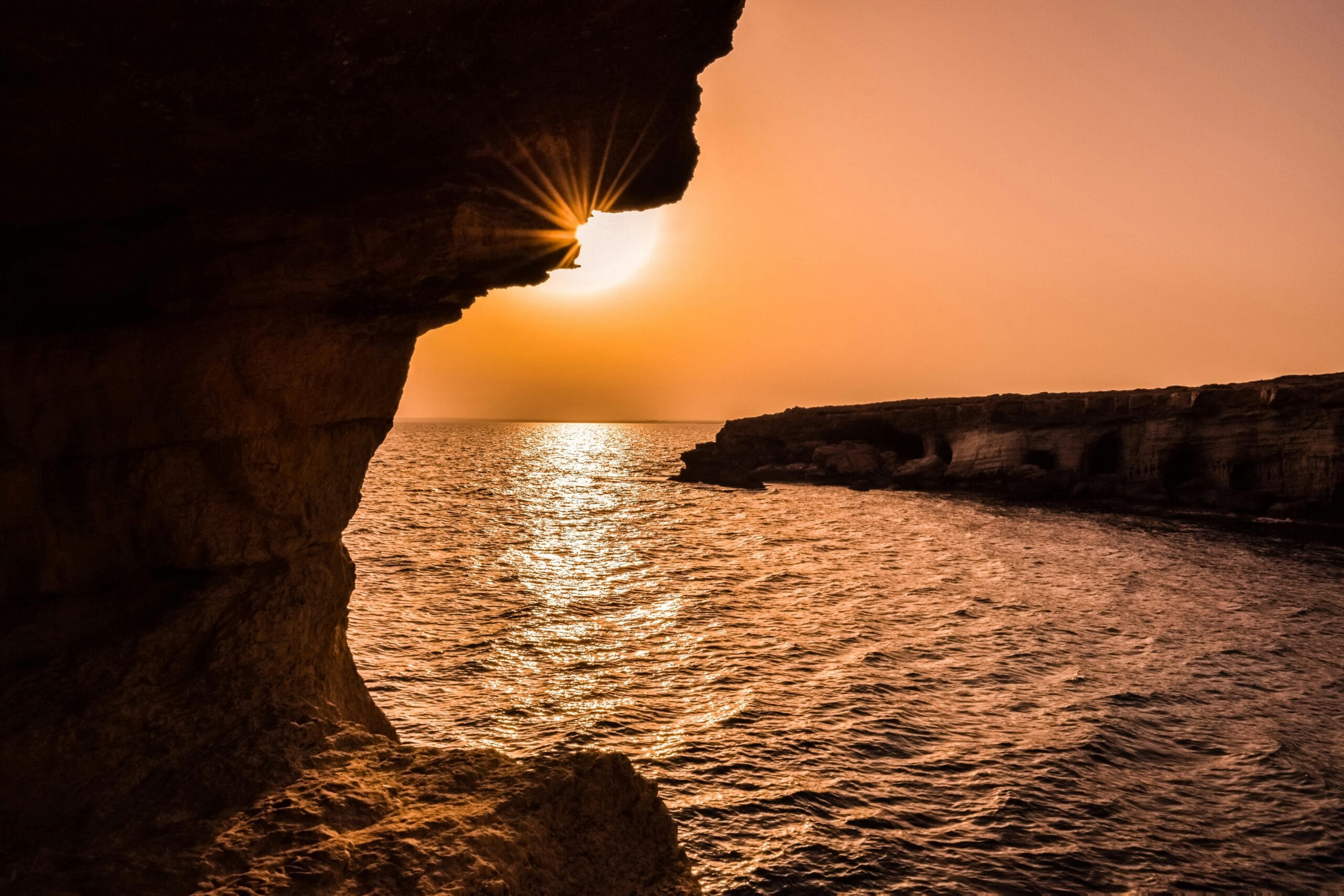 Breathtaking sunset over the ocean viewed from a Cyprus sea cave, creating a serene seascape.