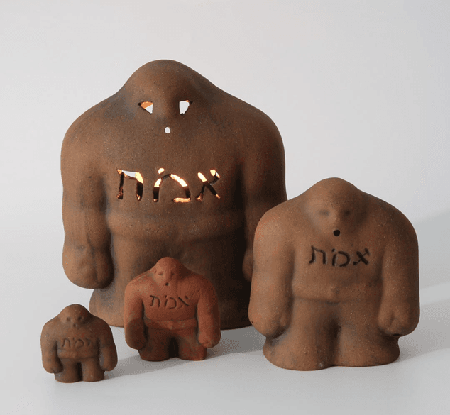 Clay figurines representing the Golem of Prague, a figure from Jewish folklore and mythology, inscribed with Hebrew letters, varying in size and color.