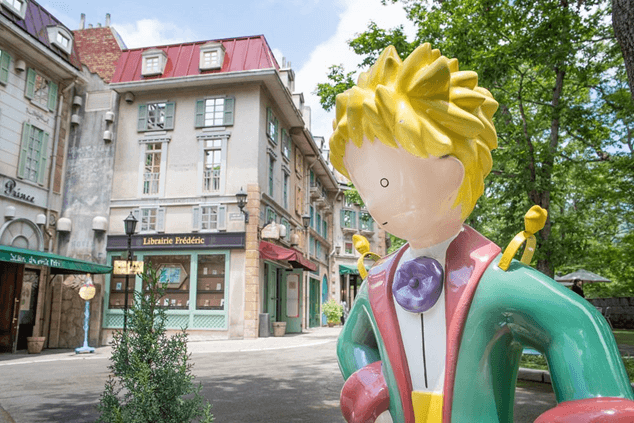 Life-sized statue of the Little Prince in a themed museum setting illustrating the cultural homage to Antoine de Saint-Exupéry's book.