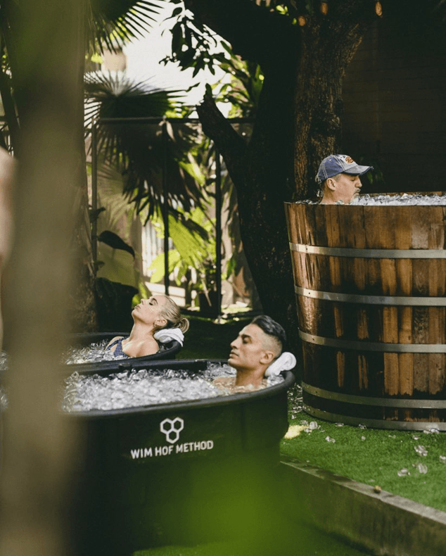 People practicing Wim Hof Method ice bath cold exposure outdoors in specialized tubs.