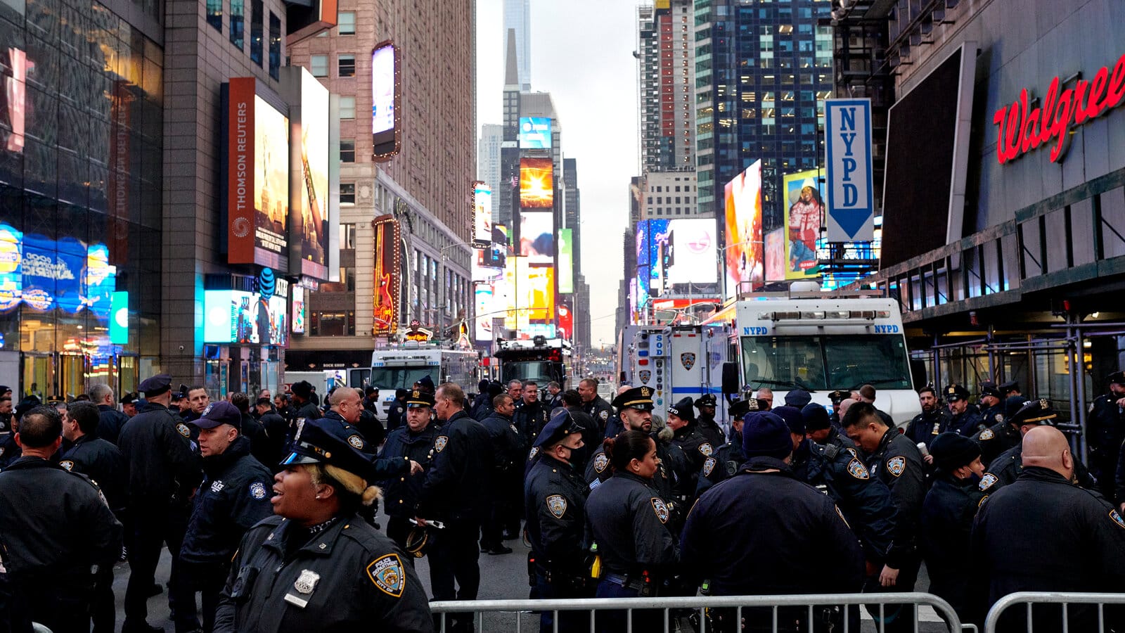 NYPD officers managing crowd control in Times Square near Planet Hollywood, a common security measure during large events like New Year's Eve.